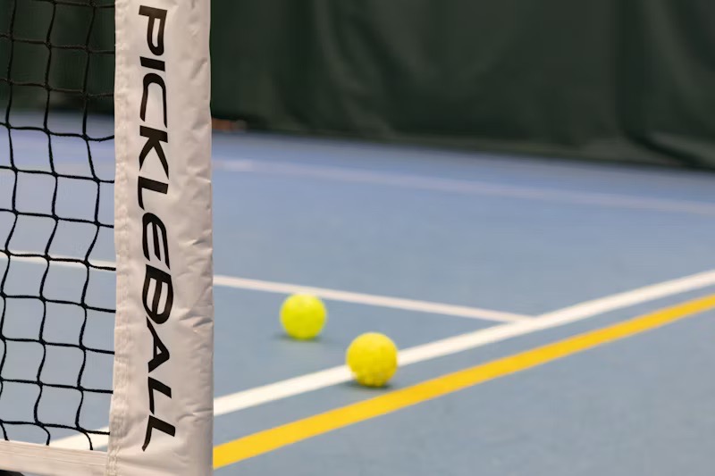 An indoor pickleball court featuring a close-up of the net with 